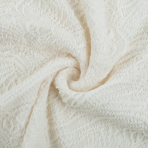 Macro detail of creamy white ruched fabric texture with elegant pleated spiral patterns