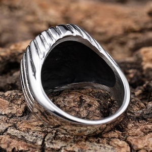 Men's minimalist stainless steel ring with vertical grooves on a natural bark background