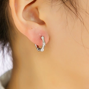 Détail de boucles d'oreilles en argent forme bambou avec une texture métallique lisse