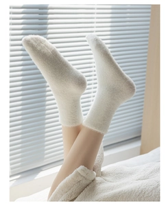 Close-up of thick white mink velvet thermal floor socks on feet in a cozy home setting