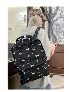Close-up of black dachshund and bow print backpack on female model in indoor setting