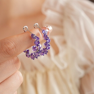 Detailed close-up of a silver hoop earring featuring faceted purple zircon beads
