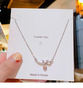 Détail du collier noeud avec une pierre rose en forme de coeur sur chaîne argent