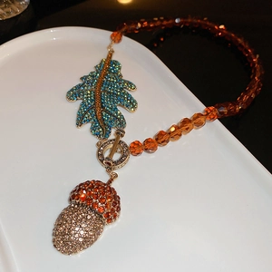 Détail du collier feuille et pomme de pin avec perles ambrées et fermoir OT vintage