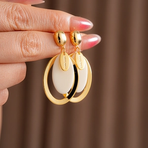 Detail of handmade oval resin earrings with gold plating and silver needles