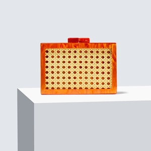 Chic green rattan and amber acrylic evening clutch bag on white geometric steps