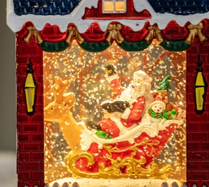 Close-up of Santa Claus and golden reindeer inside a red festive Christmas snow globe