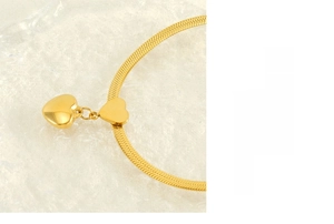 Macro detail of a gold-plated stainless steel heart pendant and refined snake chain link