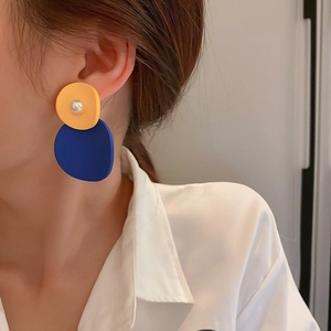 Detail of blue and yellow geometric earrings with pearl accent on a model