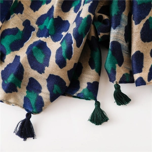 Detail of leopard print scarf with navy blue and green patterns and fringed edges