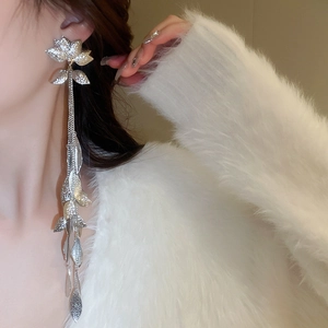 Détail de boucles d'oreilles fleurs argentées avec longues feuilles sur le mannequin