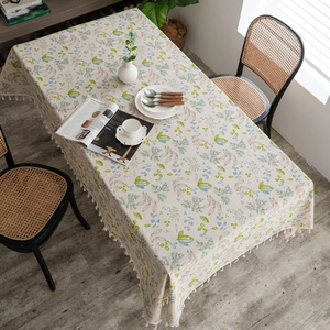 Close-up of linen table runner with green floral prints and elegant tassel edge trim