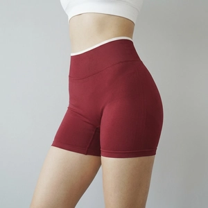 Seamless high-waisted red yoga shorts with white trim and ribbed waistband in side view