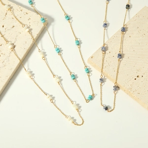 Detailed macro view of layered gold chain necklace with colorful natural stone beads