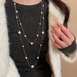 Close-up of elegant double-layered pearl necklace on grey sweater and white fur coat