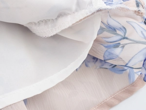 Détail du tissu en mousseline florale avec doublure blanche et finitions de surjetage