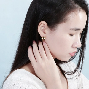 Boucles d'oreilles hibou dorées vintage avec pierres noires portées par un mannequin