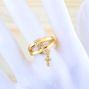 Macro detail of golden double-layer ring featuring FE letters and a zircon cross charm