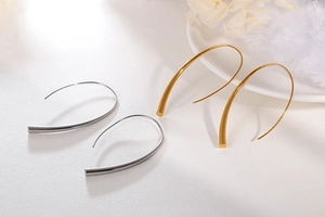 Close-up of minimalist gold and silver teardrop hook earrings with elegant curved lines