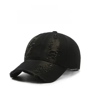 Detail of distressed black cotton baseball cap showing ripped holes and frayed edges