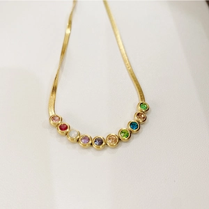 Close-up of golden snake chain necklace with multicolored zircon inlay stones