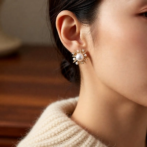 Detailed close-up of 18k gold plated pearl flower stud earrings worn by model