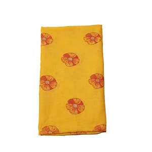 Detail of vibrant yellow scarf featuring orange floral prints and delicate gold accents