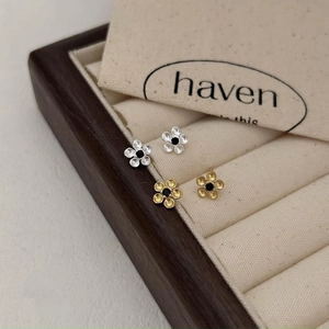 Close-up of minimalist 925 silver flower stud earrings with black stones in a box