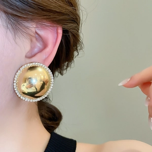 Close-up of a gold dome earring with crystal-encrusted edges worn by a model