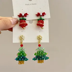 Detailed shot of handmade beaded Christmas tree earrings with festive red bows on a card