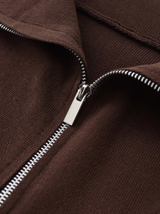 Macro shot of silver metal zipper and dark brown ribbed knit fabric texture of the jacket