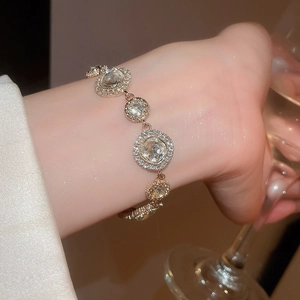 Detailansicht eines goldfarbenen Armbands mit runden und quadratischen Edelsteingliedern