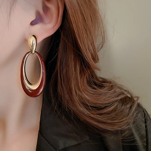 Close-up of vintage oval enamel earrings in burgundy and gold on a model