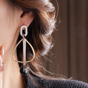 Gros plan détaillé de boucles d'oreilles géométriques or et argent sur un modèle