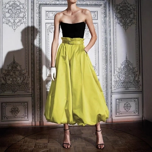 Détail d'une jupe boule en satin jaune citron à taille haute avec boucle décorative