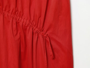 Détail d'une robe midi rouge avec cordon de serrage et texture de tissu plissé