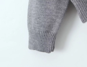 Gros plan détaillé des poignets côtelés d'un gilet en maille grise au tissu texturé