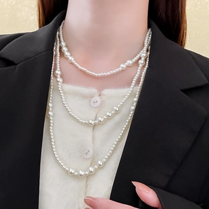 Close-up of elegant multi-layer white pearl necklace with varying bead sizes on a model