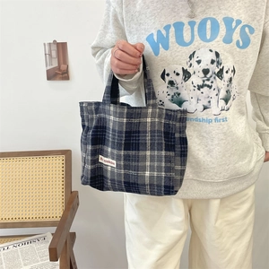 Detailed close-up of large plaid tote bag with brand label and stylish vintage pattern