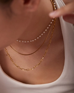 Detail of layered necklace featuring white pearls, box chain and golden paperclip link