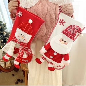 Detail of 3D snowman and Santa Claus knitted Christmas stockings held by hand