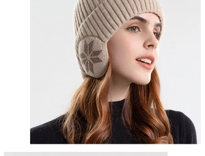 Detail van de beige gebreide wintermuts met oorflappen en een sneeuwvlokpatroon erop