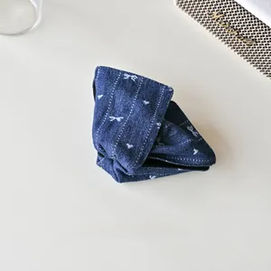 Détail de la pince à cheveux en denim bleu foncé avec broderie nœud et cœur blanc