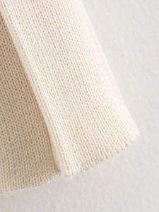Close-up of cream white knit fabric showing thick texture and fine stitching detail