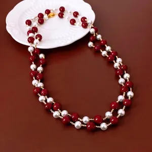 Double-layered red and white vintage pearl necklace with gold accents on a leather background