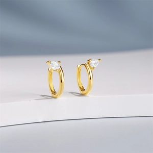 Macro shot of gold hoop earrings with pear-cut crystal drops on a white stand