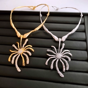 Détail du collier avec pendentif araignée orné de strass brillants sur plateau noir