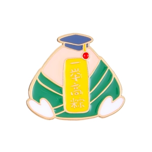 Macro detail of enamel graduation pin featuring cartoon Zongzi with academic cap and gold trim