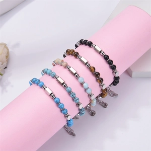 Adjustable stainless steel square turquoise bead bracelets with natural stones on a pink display