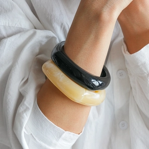 Close-up of thick geometric acrylic bangles in black and marble resin on woman wrist